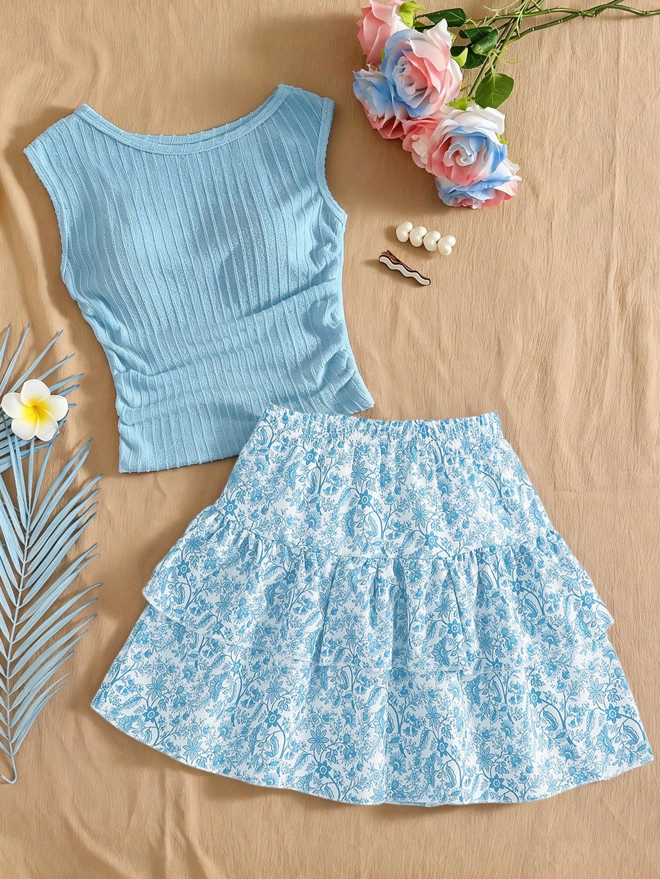 Light blue two-piece outfit set for tween girls with a sleeveless round neck vest top and a tiered ruffle cake skirt featuring a plant pattern.