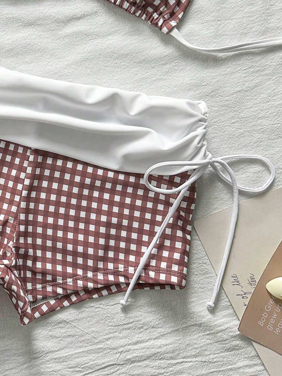 Women's halter triangle bikini top with knot detail paired with mid-waist colorblock swim shorts.