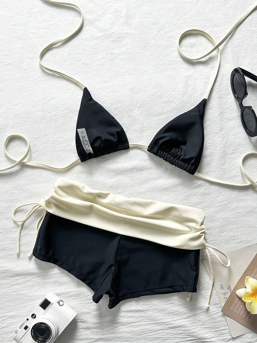 Women's halter triangle bikini top with knot detail paired with mid-waist colorblock swim shorts.