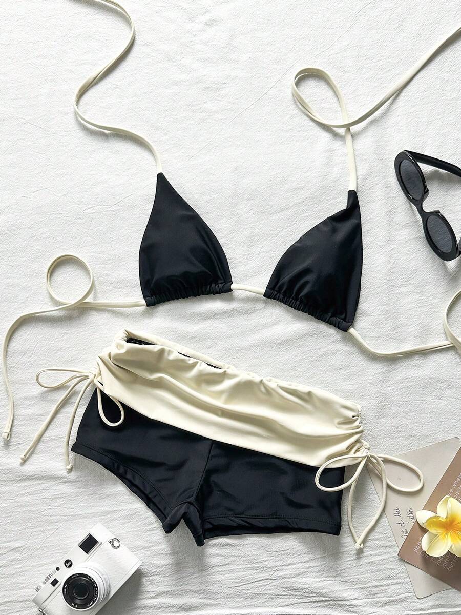 Women's halter triangle bikini top with knot detail paired with mid-waist colorblock swim shorts.