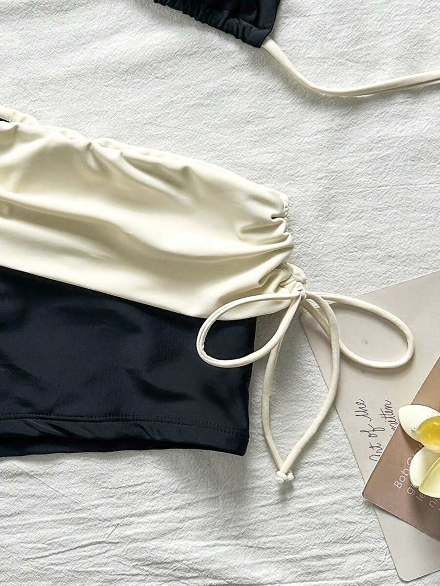 Women's halter triangle bikini top with knot detail paired with mid-waist colorblock swim shorts.