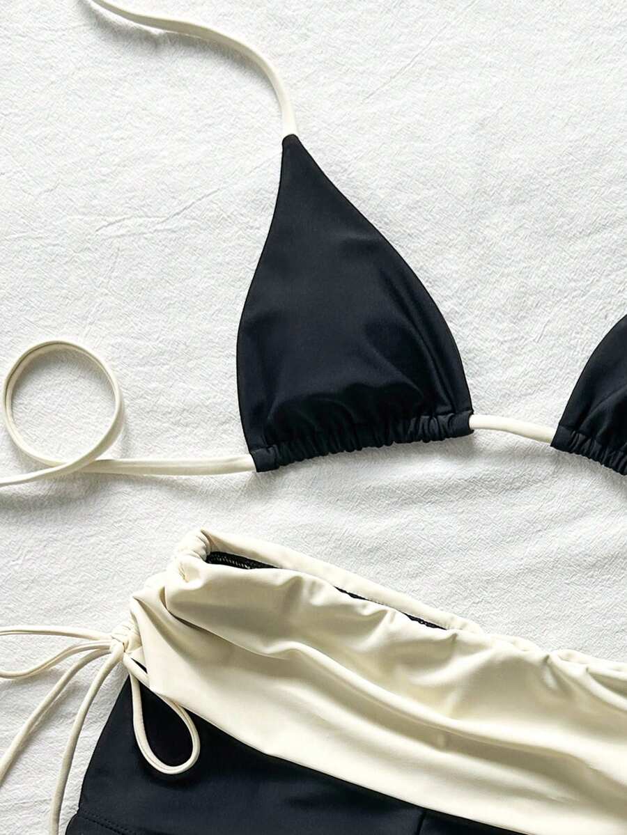 Women's halter triangle bikini top with knot detail paired with mid-waist colorblock swim shorts.