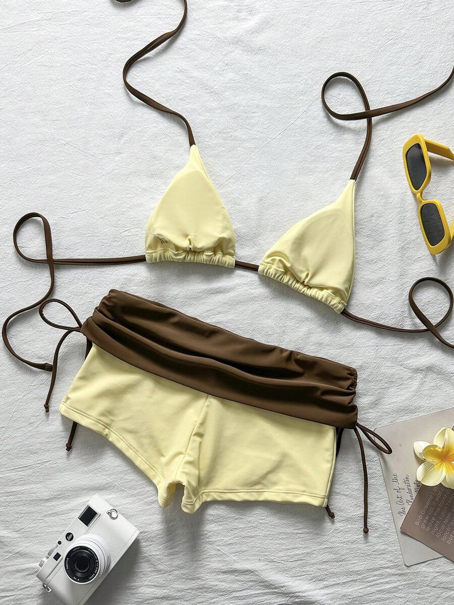 Women's halter triangle bikini top with knot detail paired with mid-waist colorblock swim shorts.