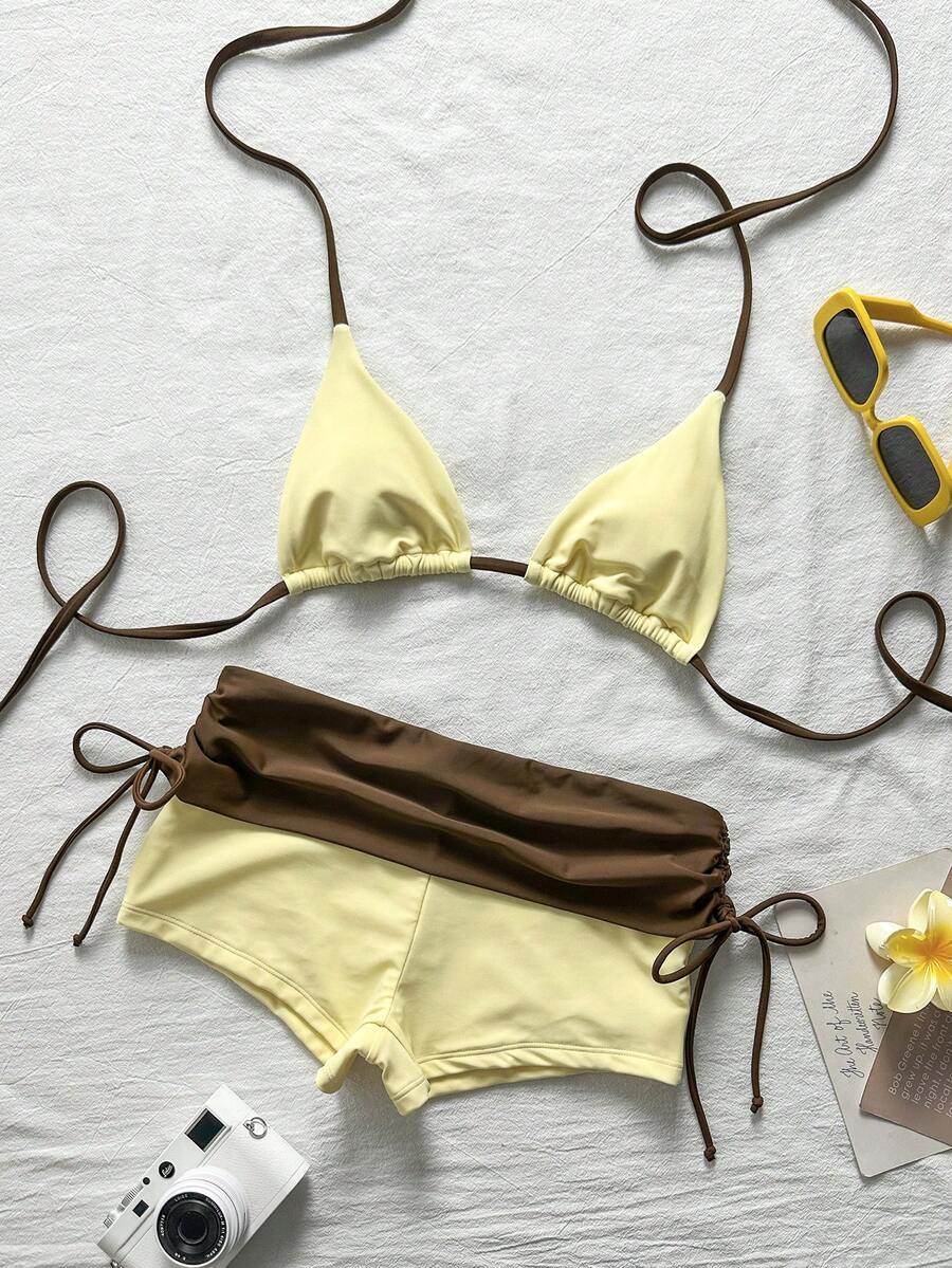 Women's halter triangle bikini top with knot detail paired with mid-waist colorblock swim shorts.
