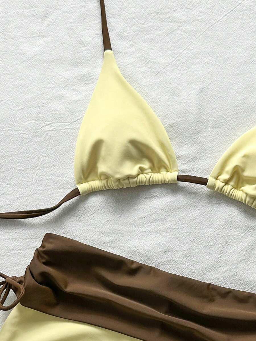 Women's halter triangle bikini top with knot detail paired with mid-waist colorblock swim shorts.