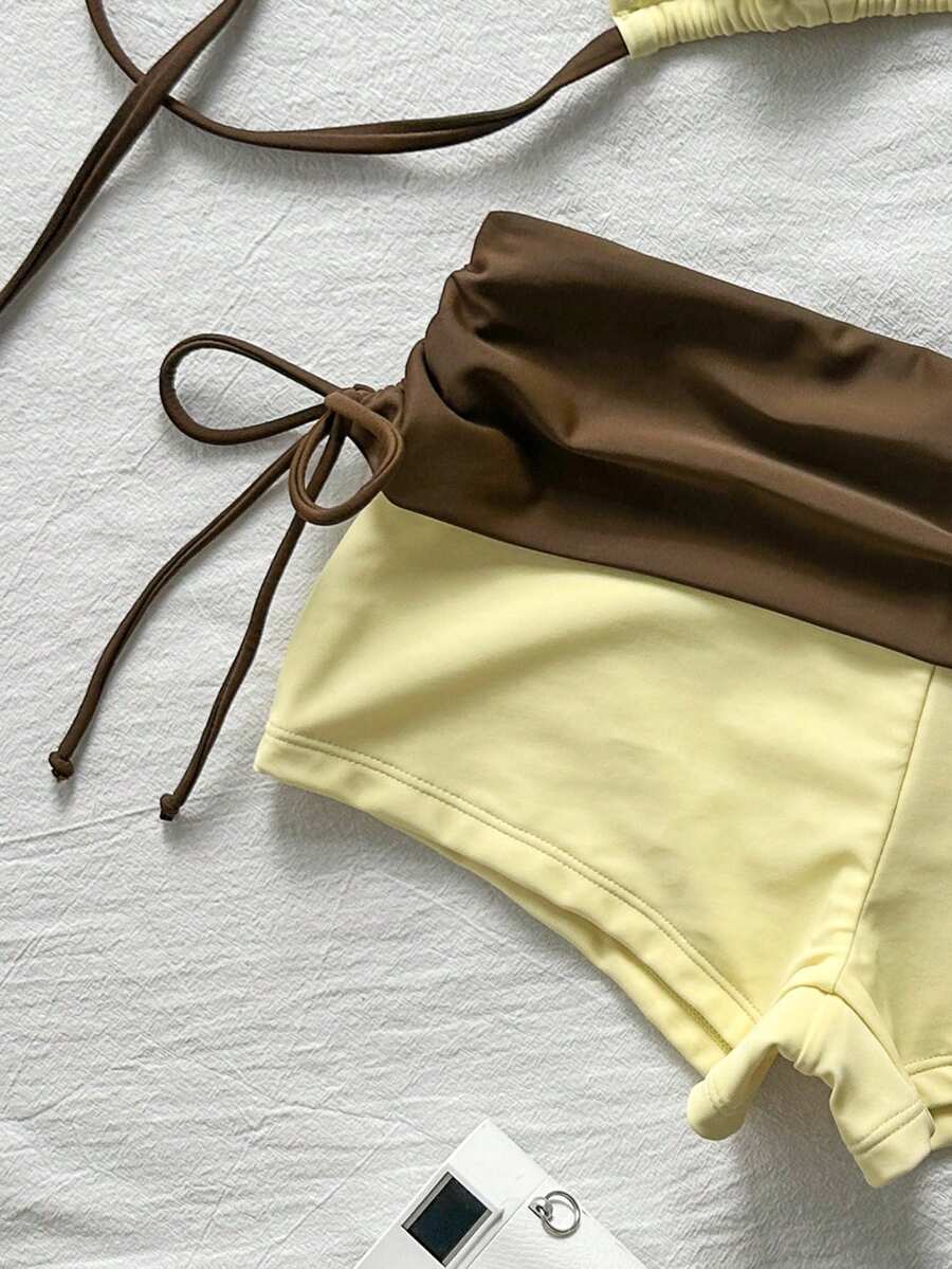 Women's halter triangle bikini top with knot detail paired with mid-waist colorblock swim shorts.