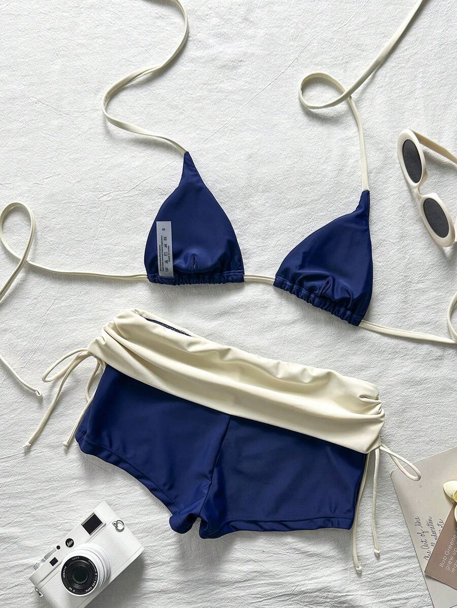 Women's halter triangle bikini top with knot detail paired with mid-waist colorblock swim shorts.