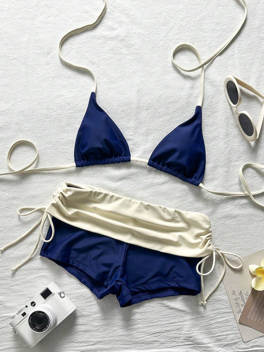 Women's halter triangle bikini top with knot detail paired with mid-waist colorblock swim shorts.