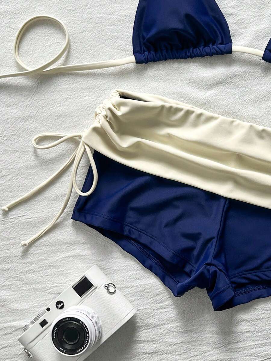 Women's halter triangle bikini top with knot detail paired with mid-waist colorblock swim shorts.