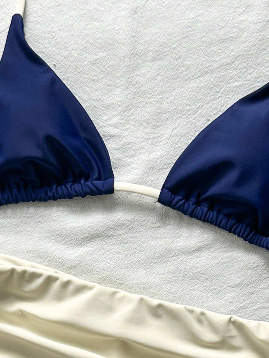 Women's halter triangle bikini top with knot detail paired with mid-waist colorblock swim shorts.
