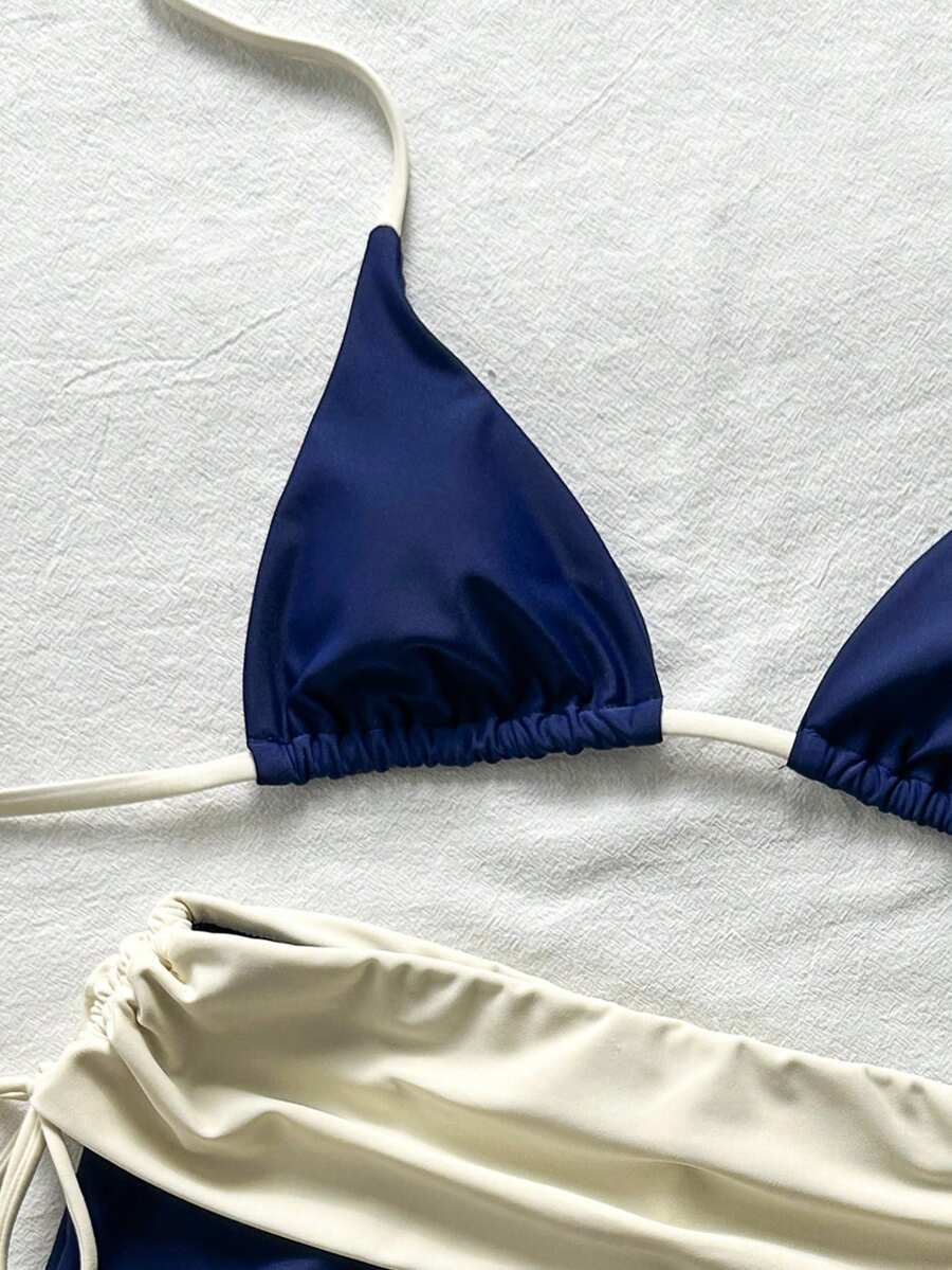 Women's halter triangle bikini top with knot detail paired with mid-waist colorblock swim shorts.