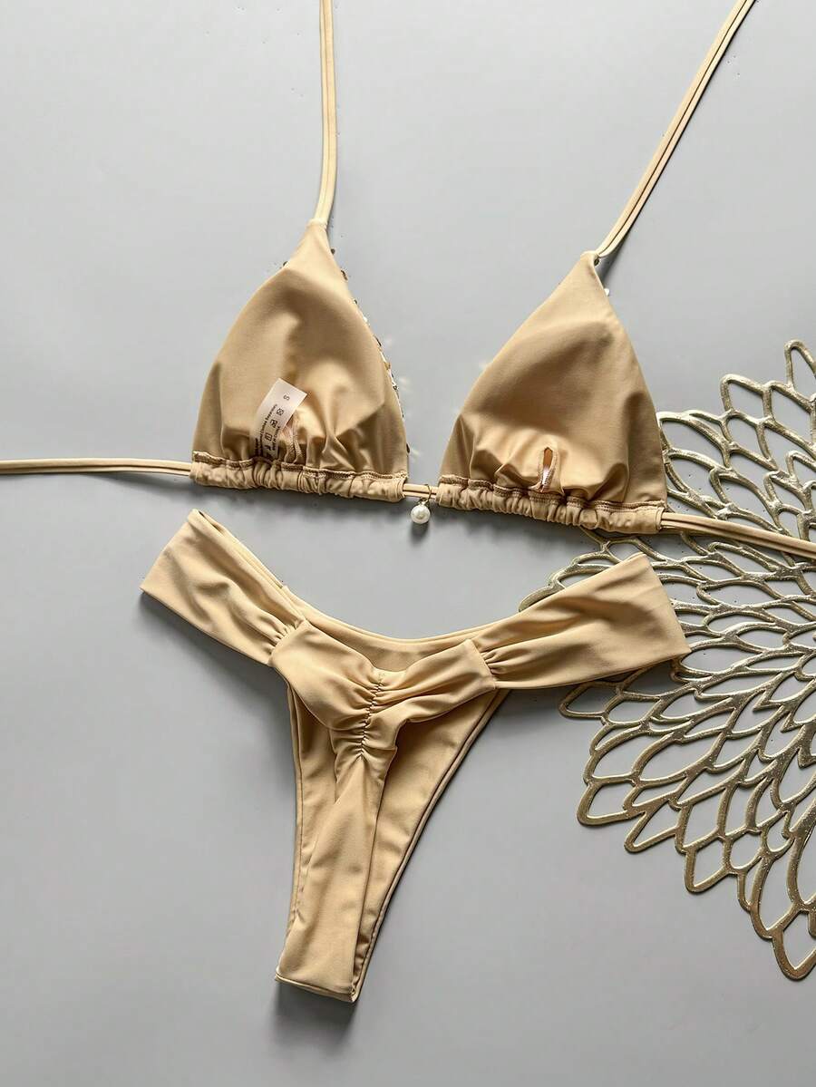 Women's 2-piece triangle cup bikini set in solid color featuring woven pearl shell decoration, halter neckline, and high-waist side-tie ruched bottoms.