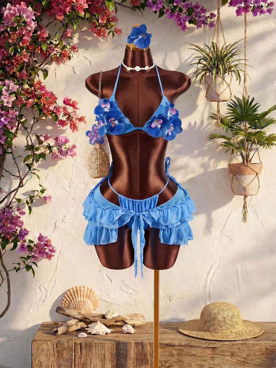 Women's 3-piece blue bikini swimwear set featuring a crop top with 3D rose accents, tie back detail, spaghetti straps, and tie-side bottoms.