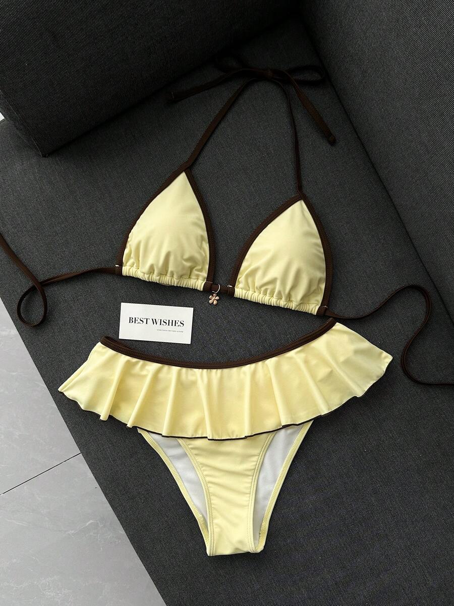 Women's 70s retro black and white polka dot bikini set featuring a halter triangle top and ultra low waist bottoms.