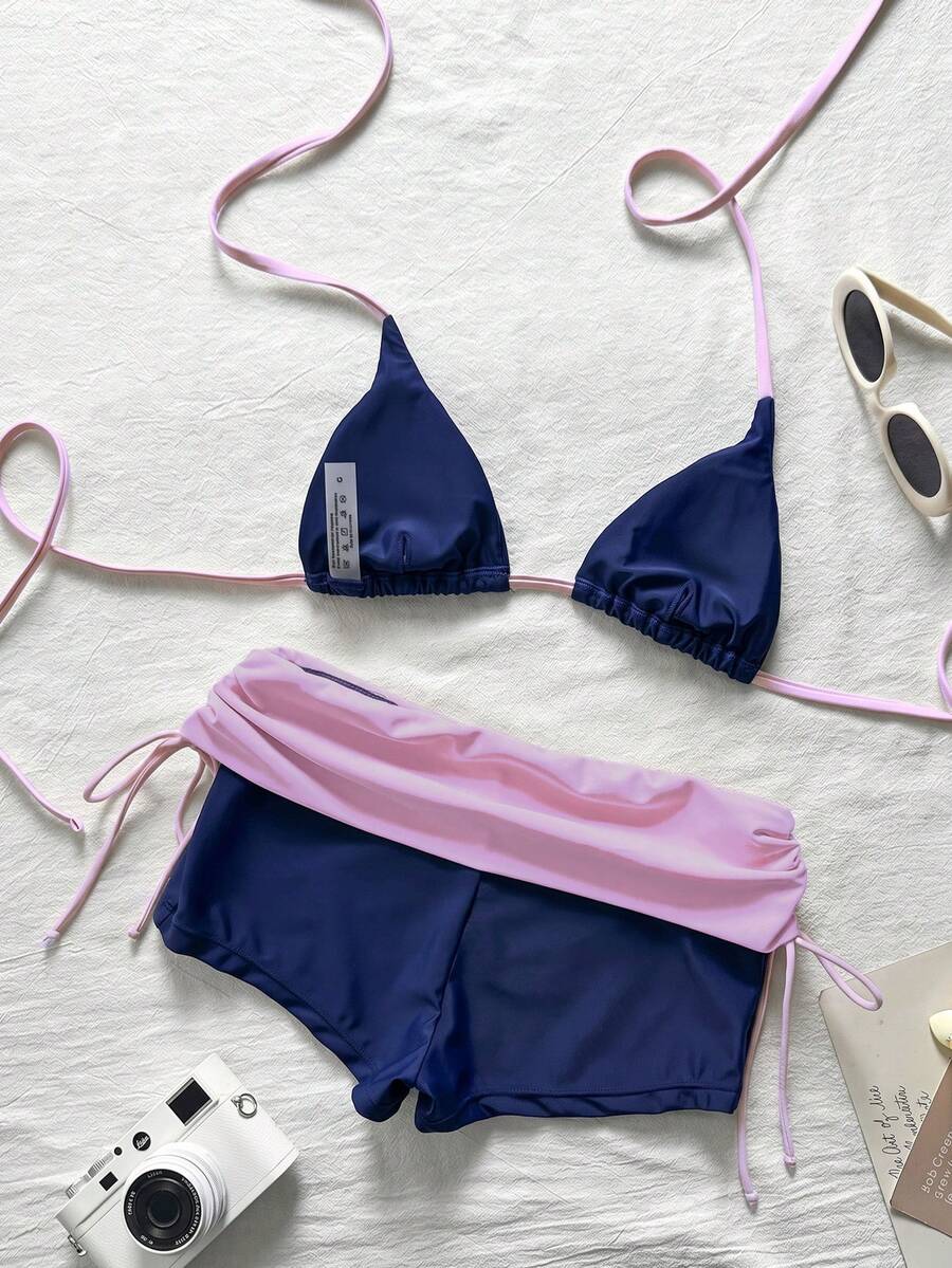 Women's halter triangle bikini top with knot detail paired with mid-waist colorblock swim shorts.