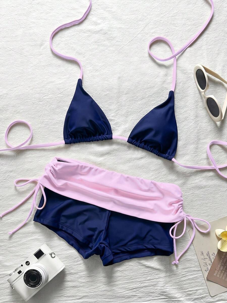 Women's halter triangle bikini top with knot detail paired with mid-waist colorblock swim shorts.