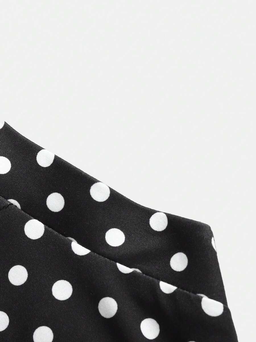 Black sleeveless halter polka dot mini dress for tween girls featuring a high waist and flared hem