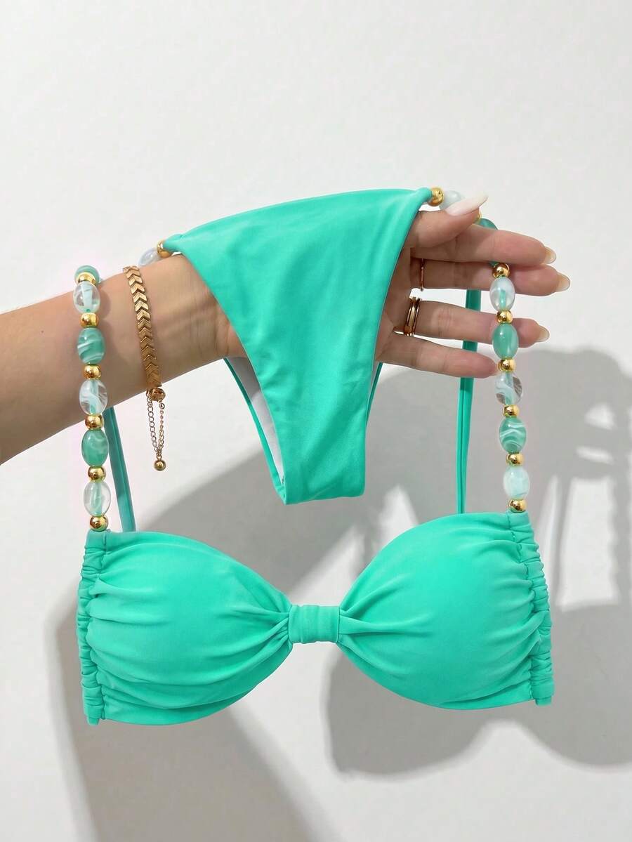Women's green halter neck bikini set featuring color-block beaded shoulder straps, back tie detail, and high cut bottoms.