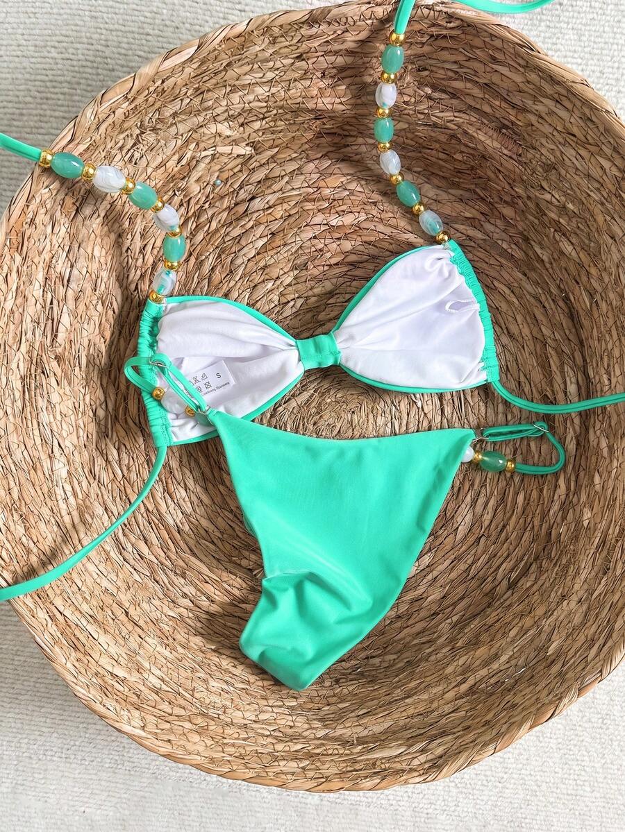 Women's green halter neck bikini set featuring color-block beaded shoulder straps, back tie detail, and high cut bottoms.