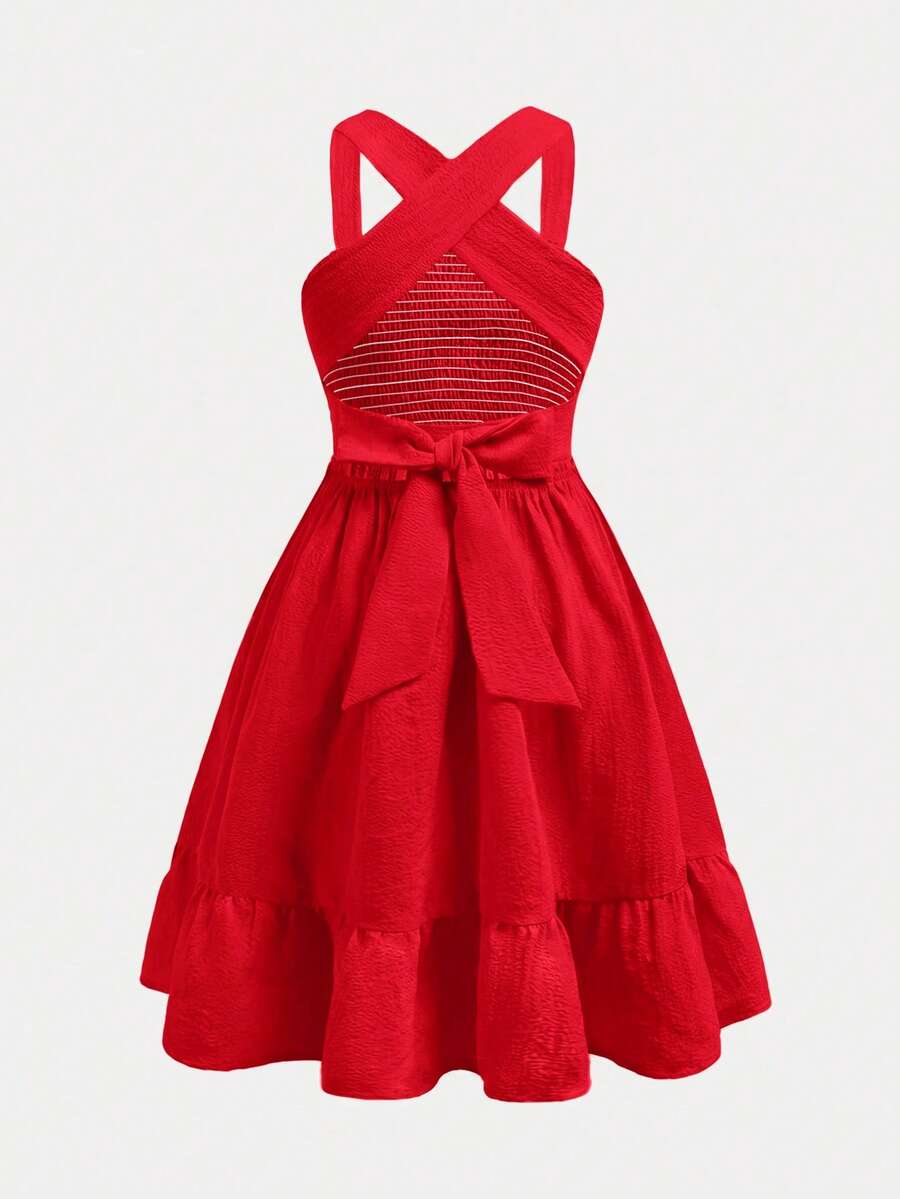 Pink sleeveless tween girls vacation dress with all-over fruit and vegetable print, strap neckline, belted high waist, cut-out detail, and flared ruffle hem.