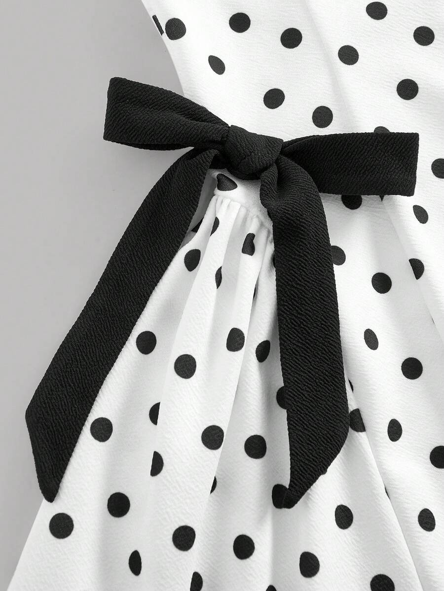Black and white polka dot cami dress for tween girls featuring a square neckline, high waist, and flared short A-line hem.