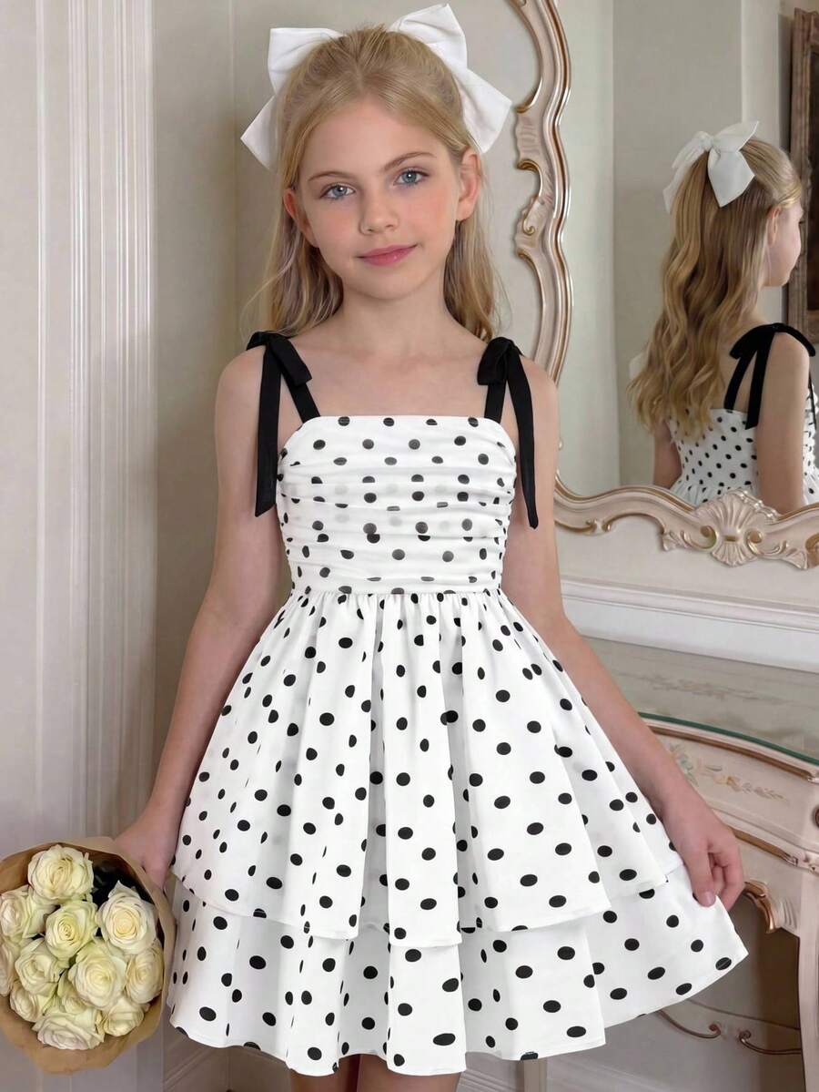 Black and white polka dot cami dress for tween girls featuring sleeveless straps, a shirred high waist, flared hem, and slim fit silhouette.