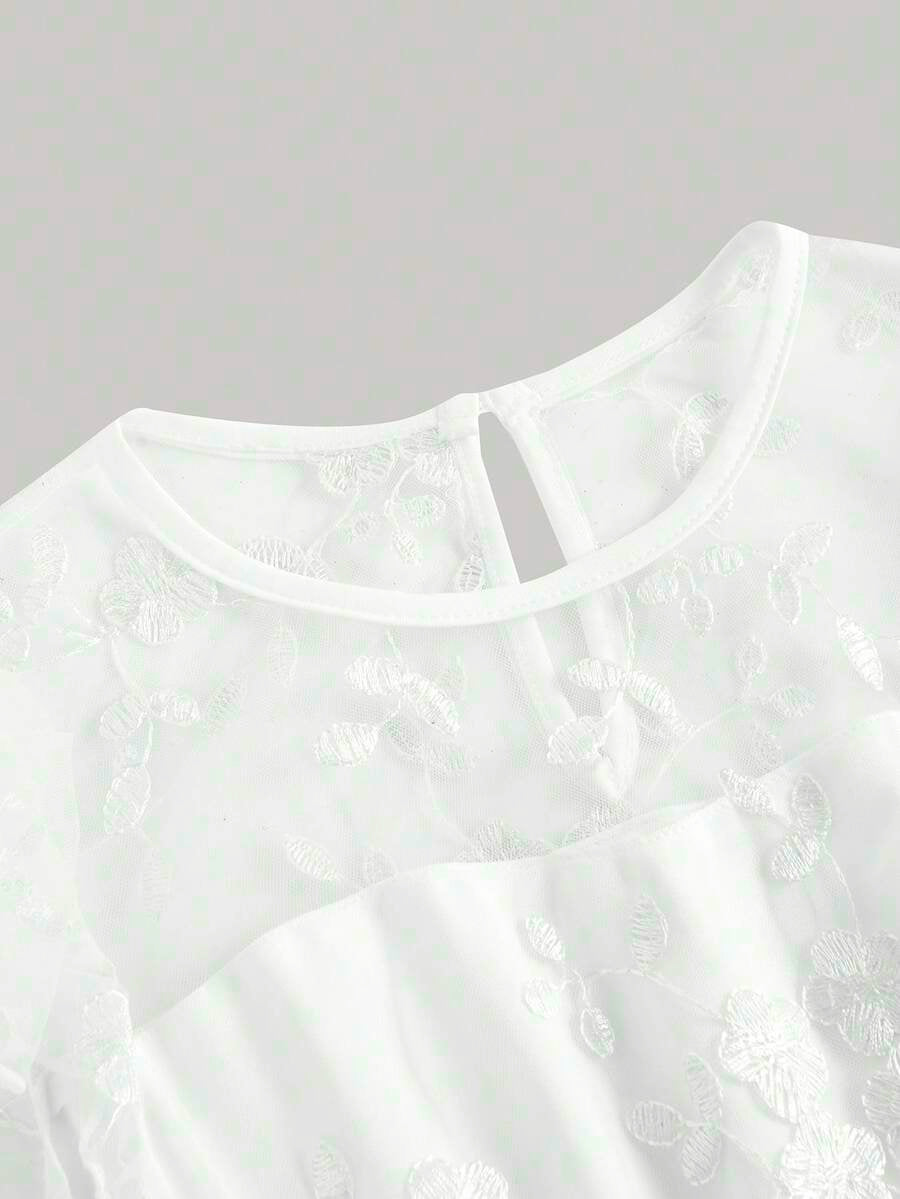 Tween girl wearing a black ditsy floral A-line short dress with V-neckline and flounce short sleeves.