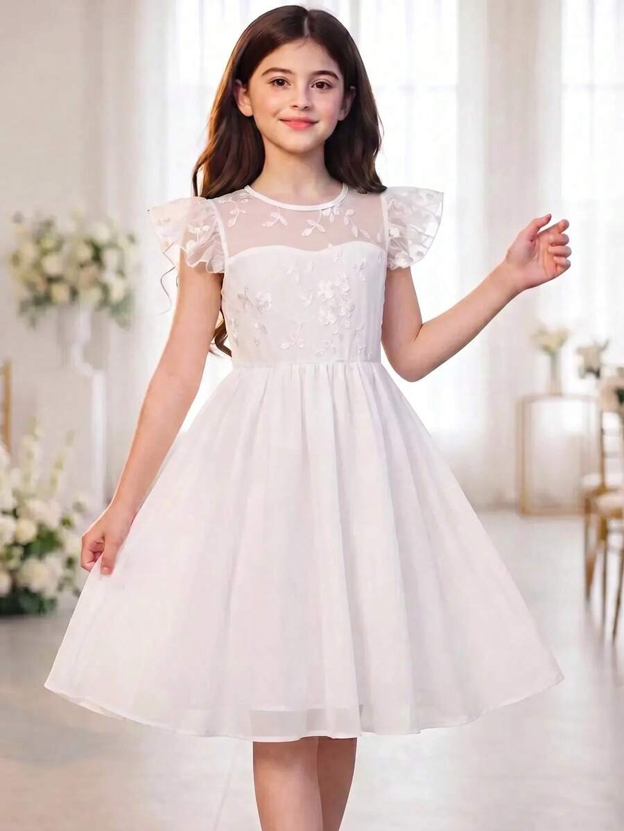 Tween girl wearing a black ditsy floral A-line short dress with V-neckline and flounce short sleeves.