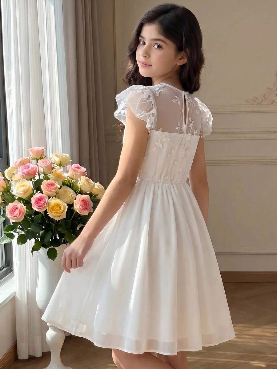 Tween girl wearing a black ditsy floral A-line short dress with V-neckline and flounce short sleeves.