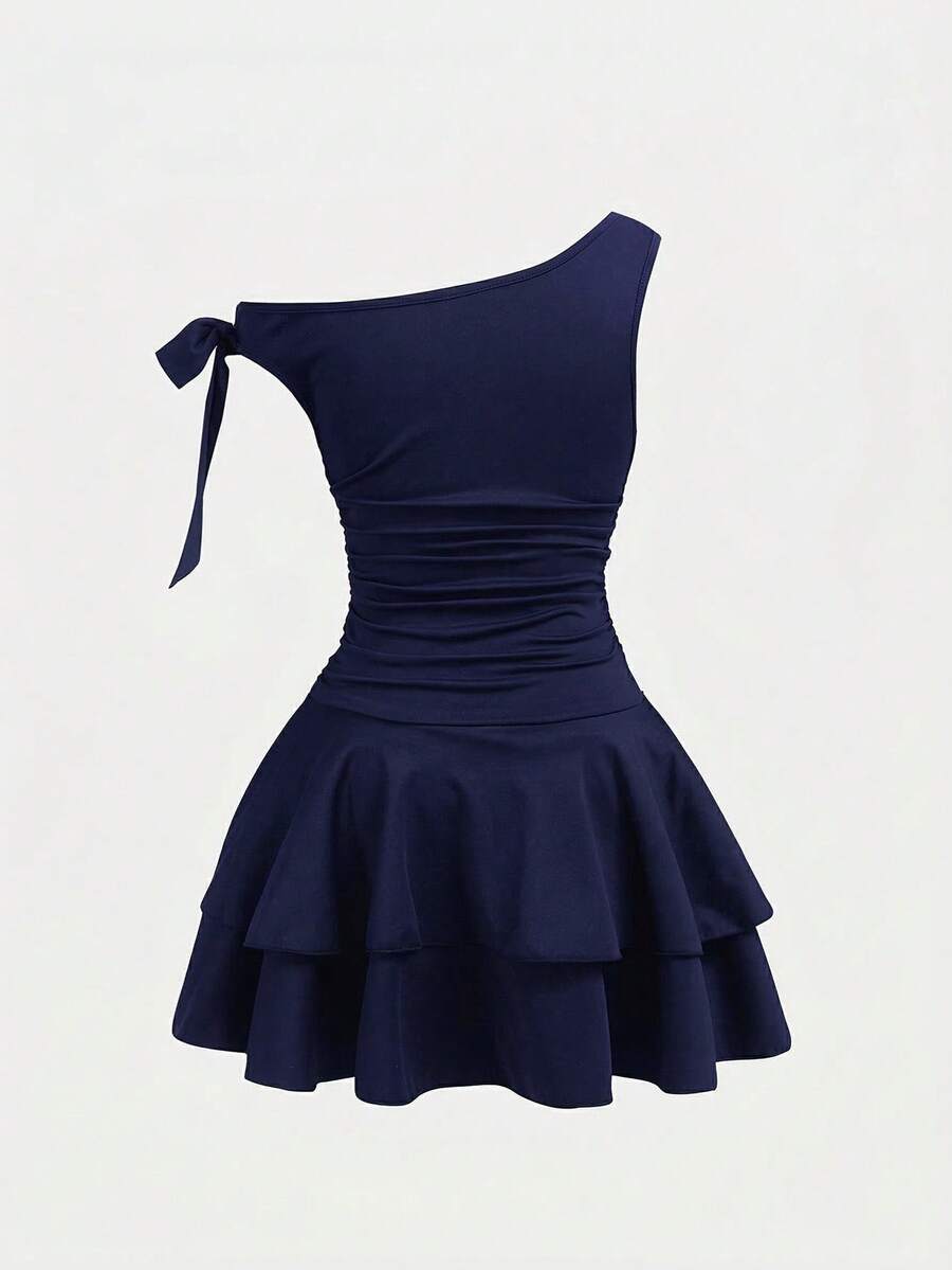 Tween girl wearing an apricot asymmetrical tiered sleeveless party dress with an A-line silhouette.