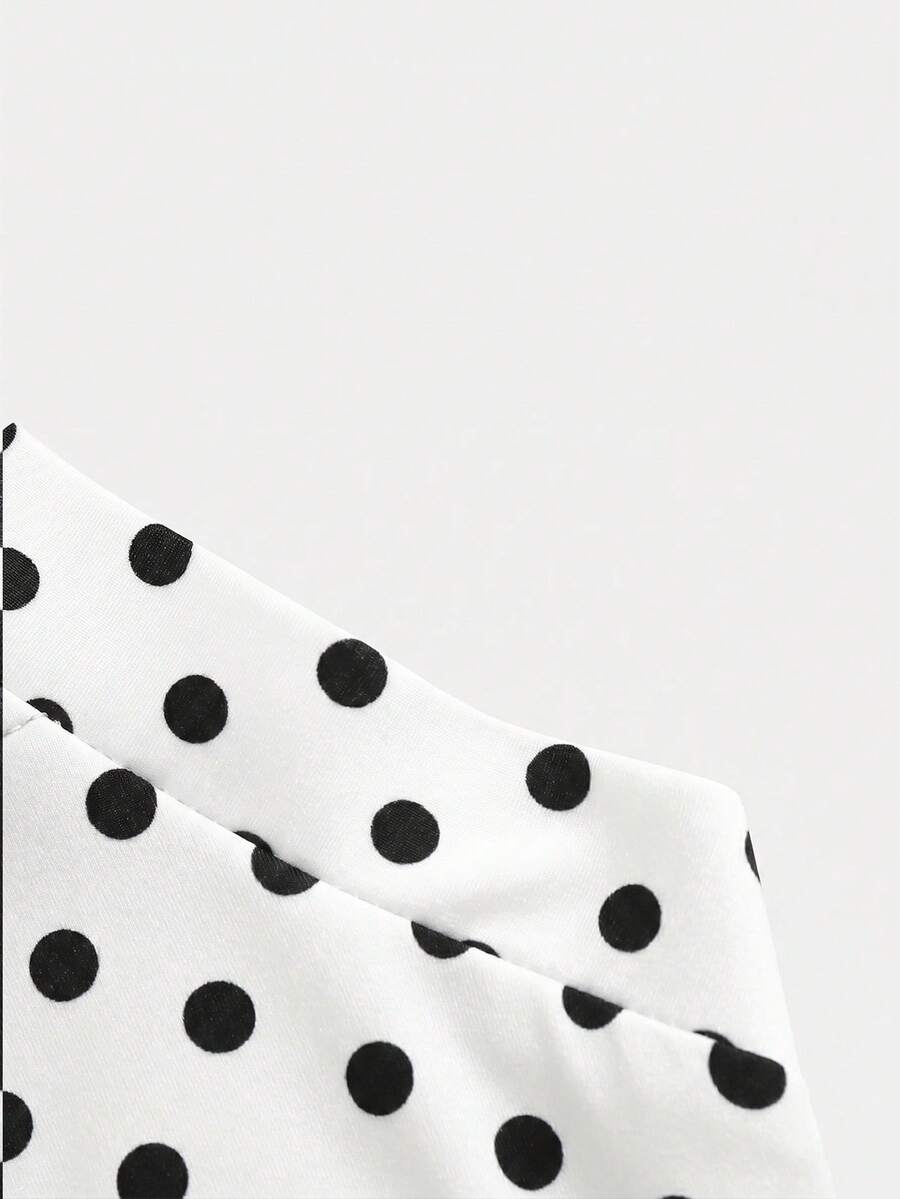Black sleeveless halter polka dot mini dress for tween girls featuring a high waist and flared hem