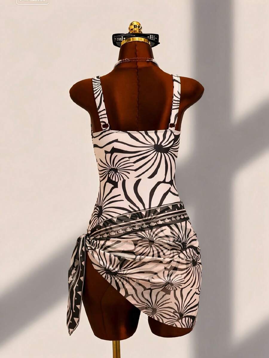 Women's black floral print plunge neck one-piece swimsuit featuring cut-out detail paired with a matching knee-length mesh cover-up skirt