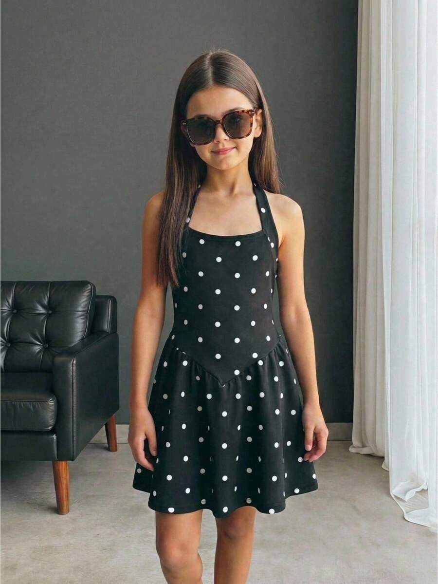 Black sleeveless halter polka dot mini dress for tween girls featuring a high waist and flared hem