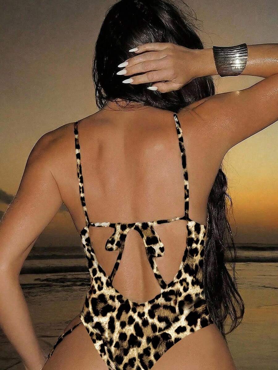 Women's black lace one-piece swimsuit featuring a deep V-neckline, spaghetti straps, backless tie-up detail, and thong bottom.