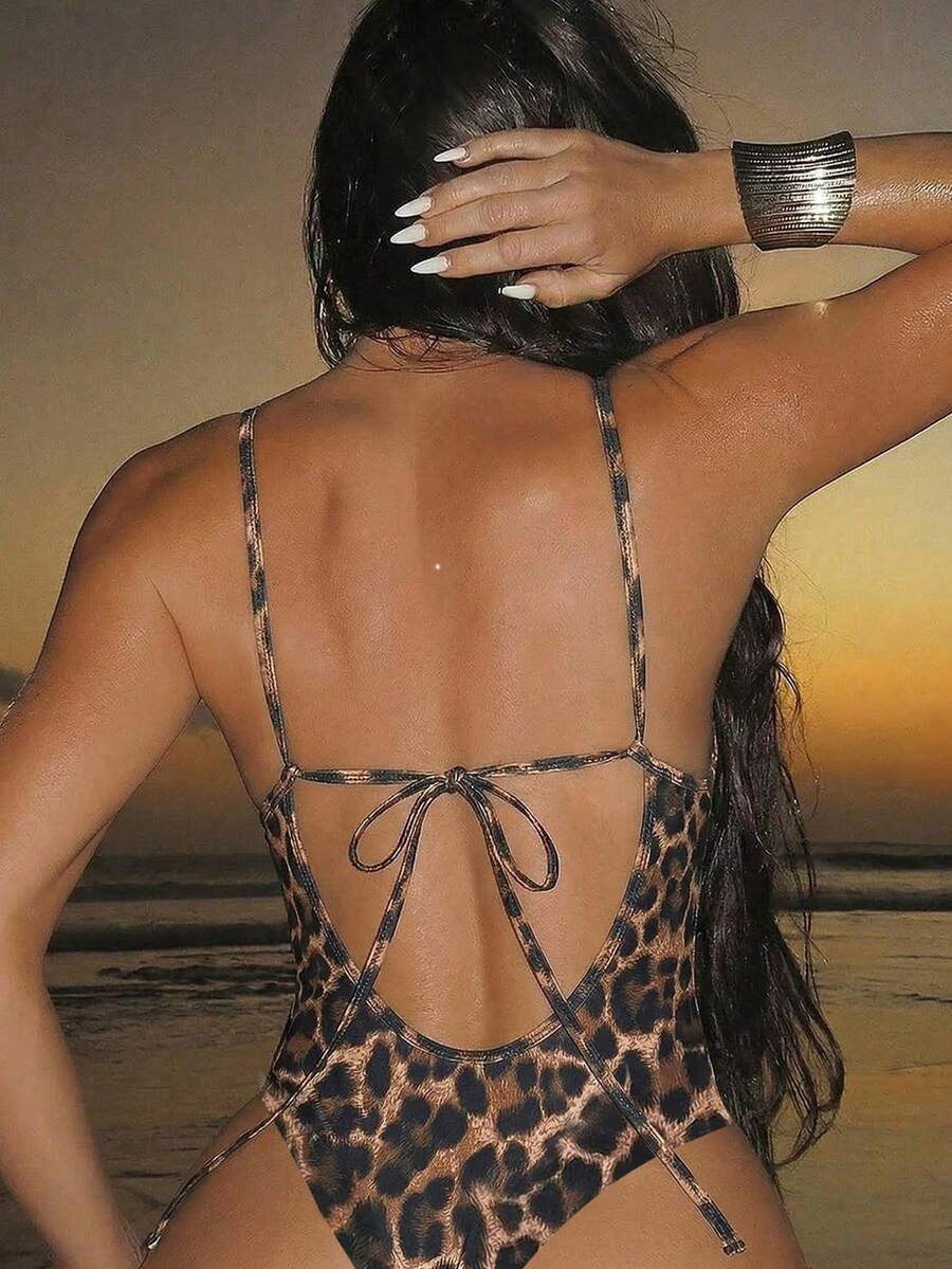 Women's black lace one-piece swimsuit featuring a deep V-neckline, spaghetti straps, backless tie-up detail, and thong bottom.