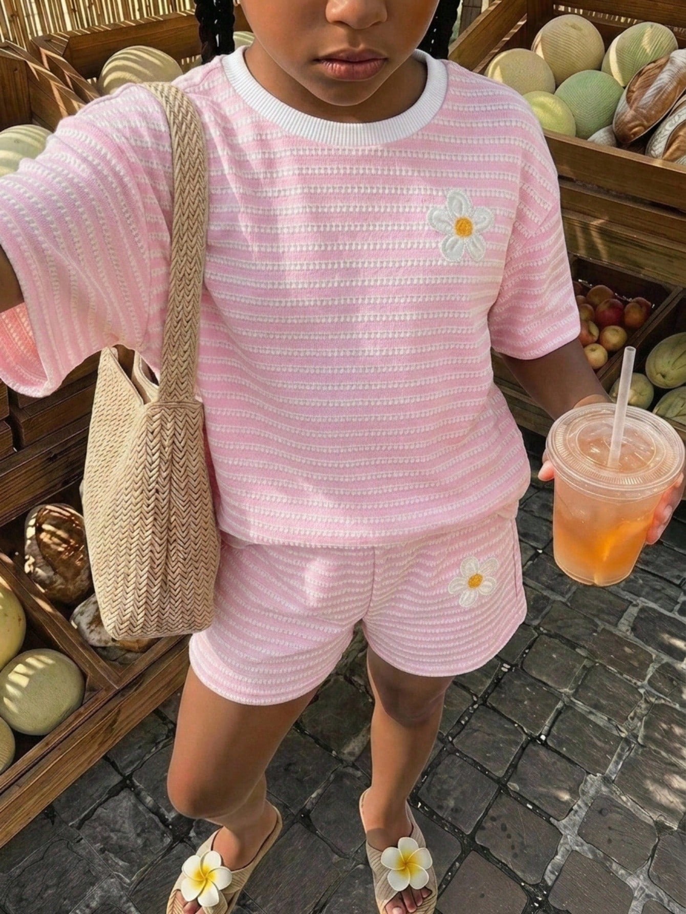 Tween girl wearing a black and white striped drop-shoulder crew neck t-shirt with bow embroidery paired with matching tie-waist shorts.