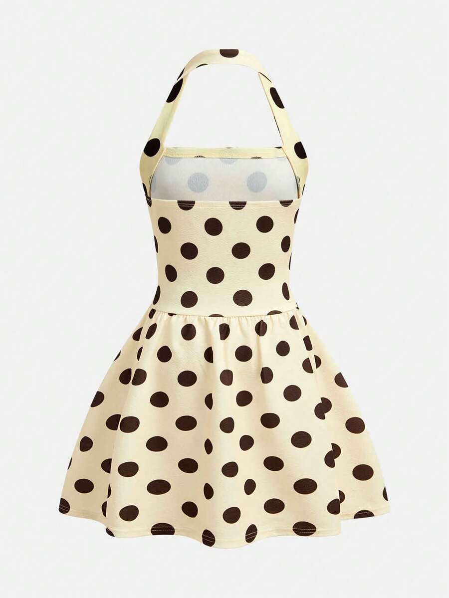 Tween girl wearing a black and white polka dot tiered cami dress with shoulder straps, a high waist, and a ruffle layered hem.