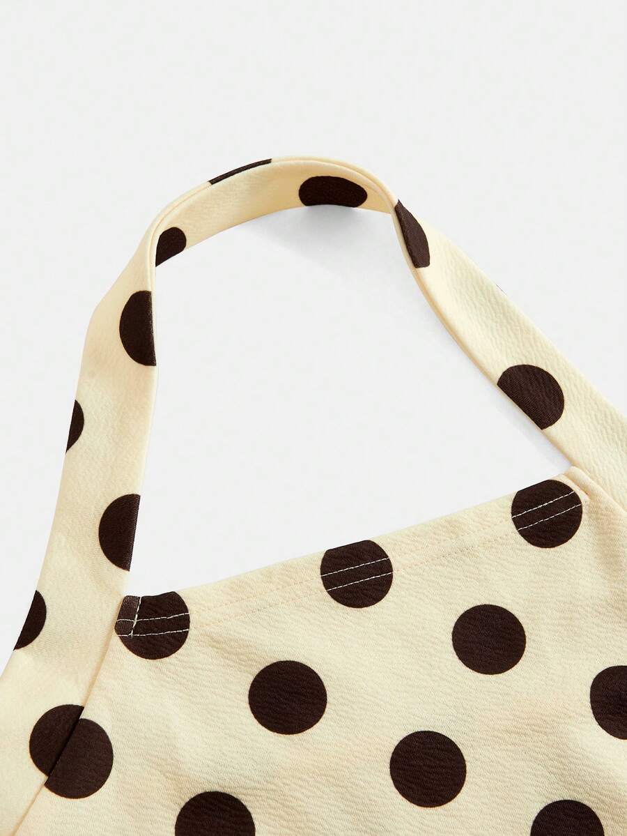 Tween girl wearing a black and white polka dot tiered cami dress with shoulder straps, a high waist, and a ruffle layered hem.