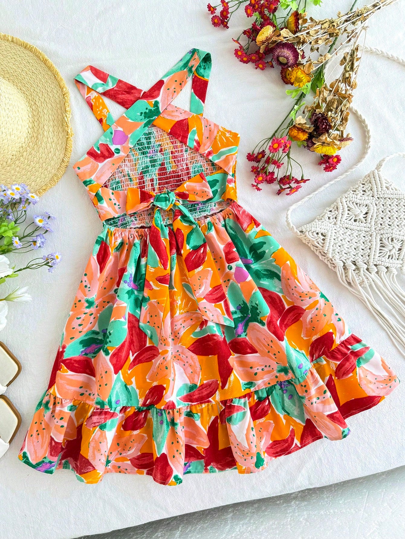 Pink sleeveless tween girls vacation dress with all-over fruit and vegetable print, strap neckline, belted high waist, cut-out detail, and flared ruffle hem.