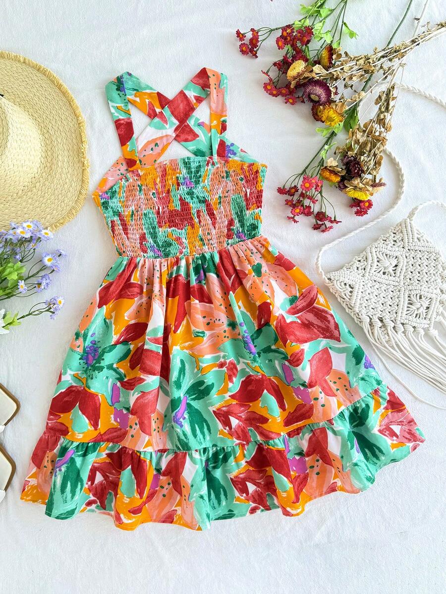 Pink sleeveless tween girls vacation dress with all-over fruit and vegetable print, strap neckline, belted high waist, cut-out detail, and flared ruffle hem.