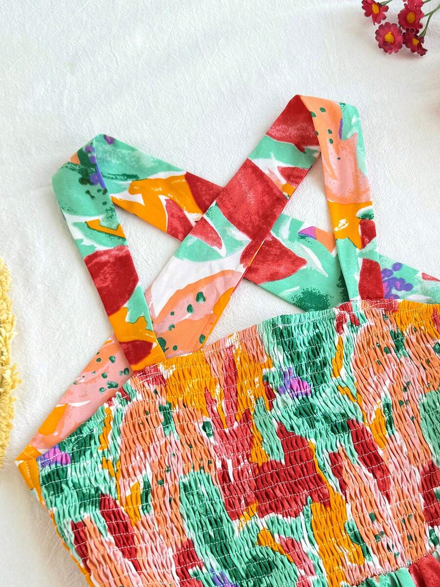 Pink sleeveless tween girls vacation dress with all-over fruit and vegetable print, strap neckline, belted high waist, cut-out detail, and flared ruffle hem.