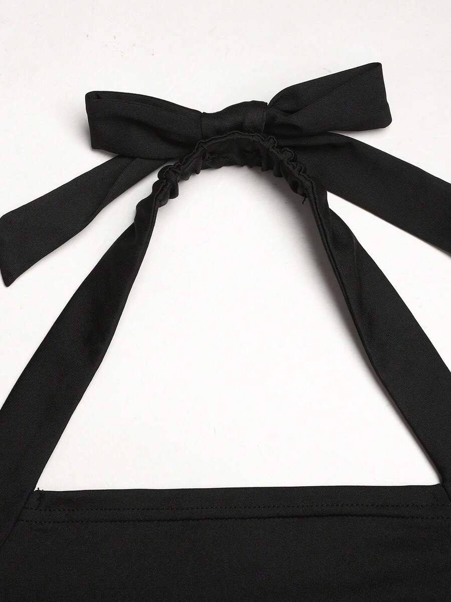 Black sleeveless halter polka dot mini dress for tween girls featuring a high waist and flared hem