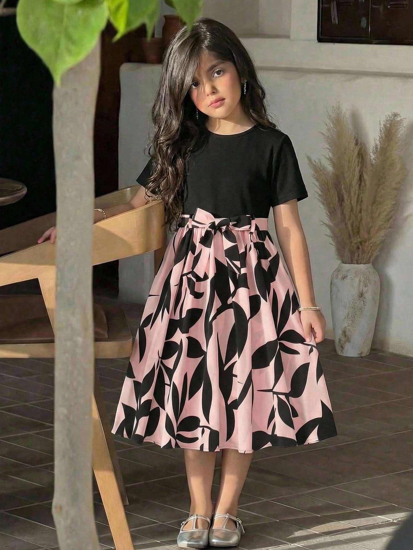 Tween girl wearing an apricot short sleeve A-line dress featuring a round neck, high waist with a belt, and flared hem.