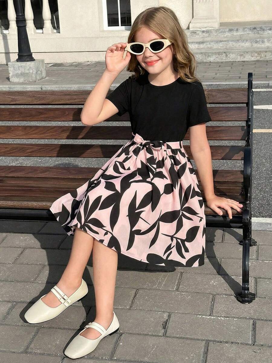 Tween girl wearing an apricot short sleeve A-line dress featuring a round neck, high waist with a belt, and flared hem.