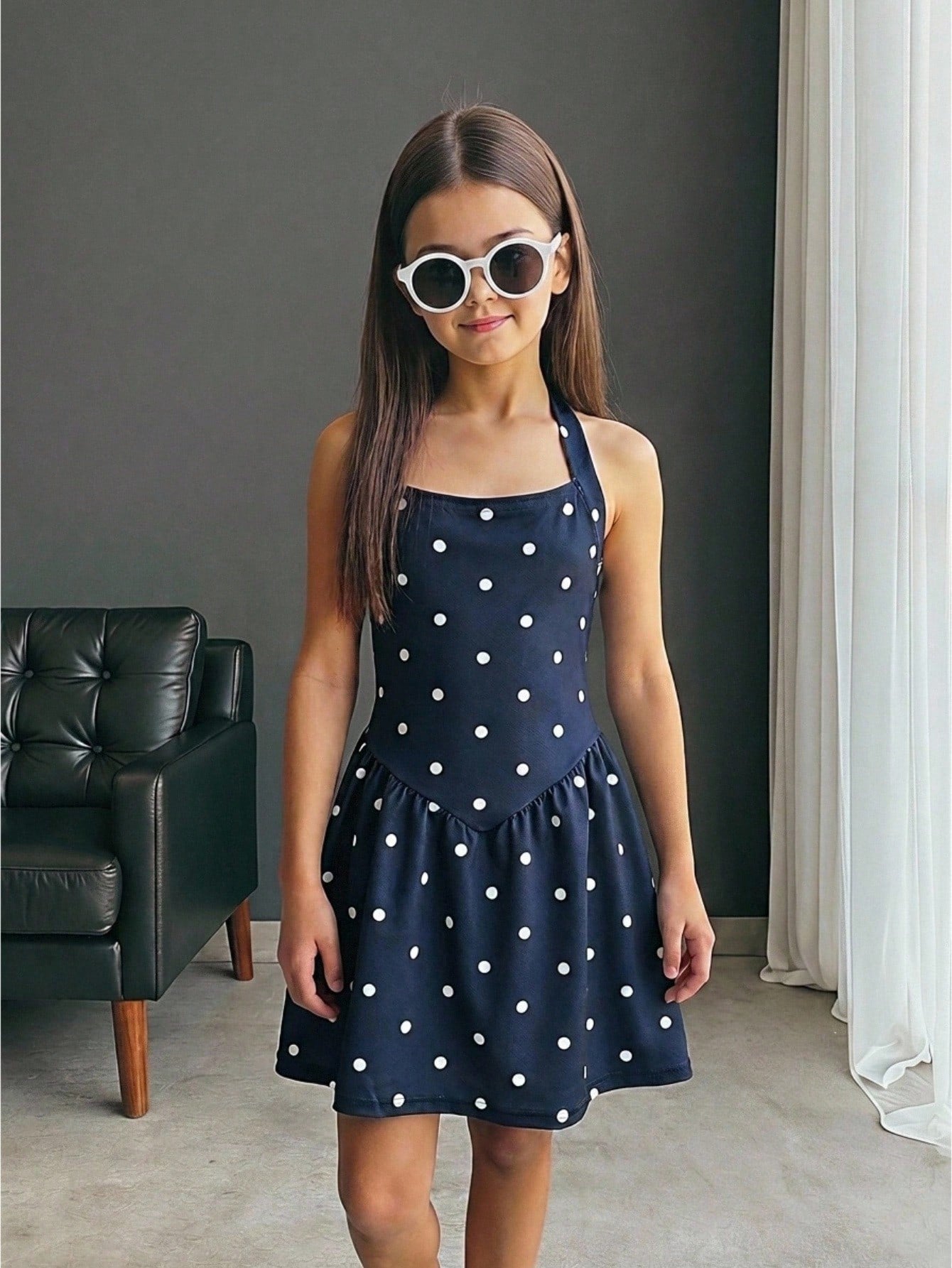 Black sleeveless halter polka dot mini dress for tween girls featuring a high waist and flared hem