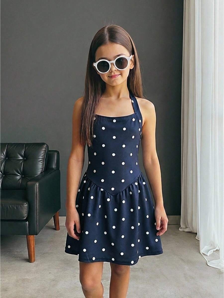 Black sleeveless halter polka dot mini dress for tween girls featuring a high waist and flared hem