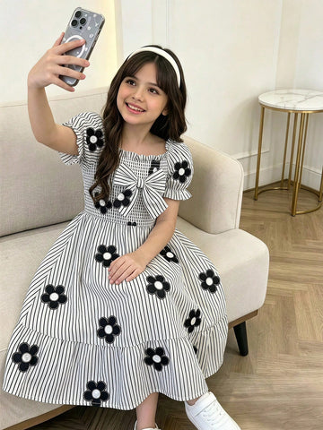 Tween girl wearing a black and white off-the-shoulder floral midi dress featuring short puff sleeves, high waist, and flounce hem.