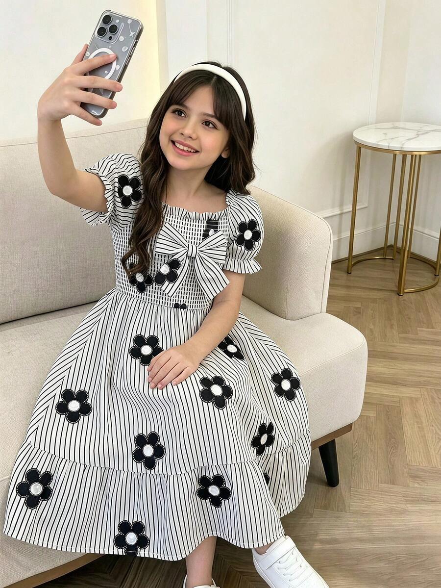 Tween girl wearing a black and white off-the-shoulder floral midi dress featuring short puff sleeves, high waist, and flounce hem.