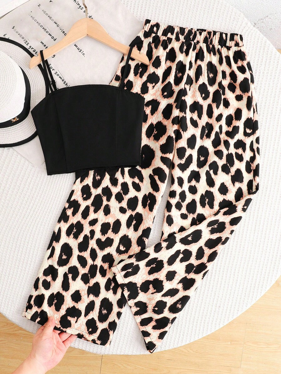 Tween girl wearing a black sleeveless spaghetti strap camisole top with 3D bow decor and matching leopard print wide leg long pants.
