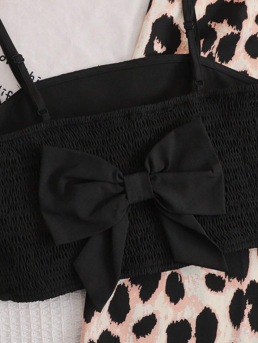 Tween girl wearing a black sleeveless spaghetti strap camisole top with 3D bow decor and matching leopard print wide leg long pants.